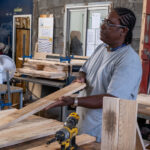 Visite des Ateliers Chantiers d'Insertion : La zone artisanale de Cambaie accueille l’association Les Palettes de Marguerite. Cette structure gère trois Ateliers Chantiers d’Insertion menés sur le Territoire de la Côte Ouest. Les Palettes de Marguerite valorisent le bois de palettes.